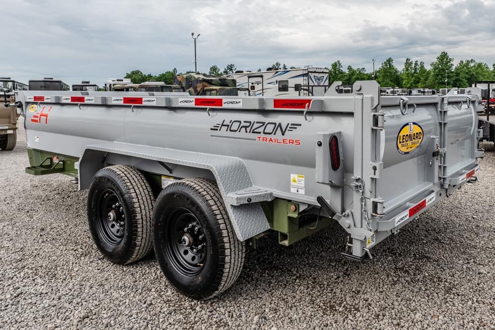 Dual-axle gray Horizon Trailers dump trailer on a gravel lot, with black wheels and red reflectors along the top edge.