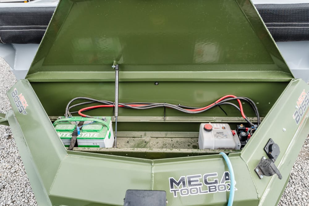 Open green MEGA TOOLBOX storage compartment showing two batteries (green and white) connected by red and black cables.