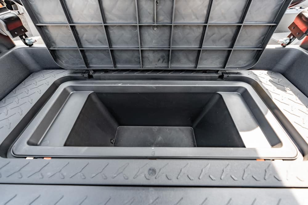Open rectangular underfloor storage compartment in a vehicle, empty with the lid raised