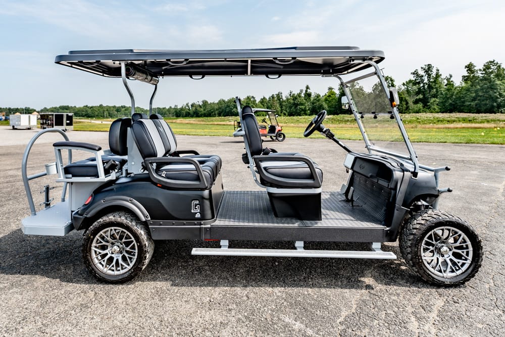 Electric four-seat golf cart with a roof, parked on an asphalt lot.