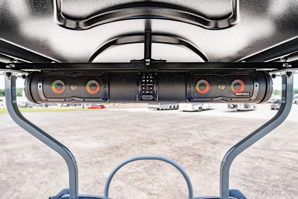 Underbody view of a dual speaker bar with LED ring lights and a central control panel mounted beneath a vehicle.