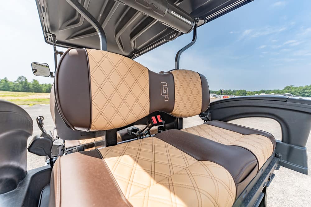 Beige quilted leather pilot seat and backrest inside a helicopter cockpit, with a red seatbelt buckle nearby.