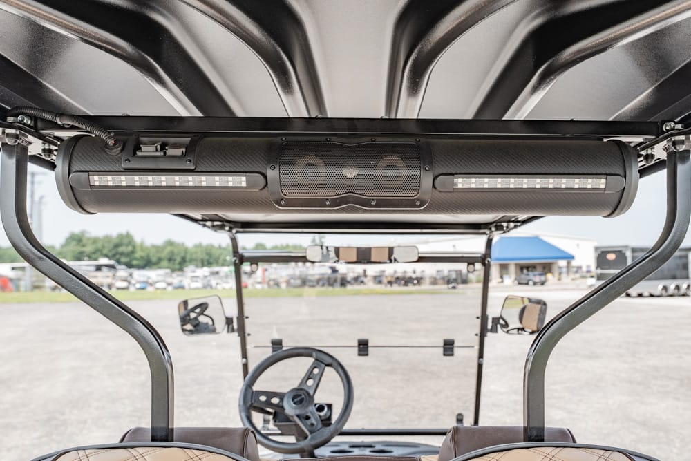 Front-facing view of a golf cart interior, showing the steering wheel, seats, and a large overhead LED light bar mounted under the roof