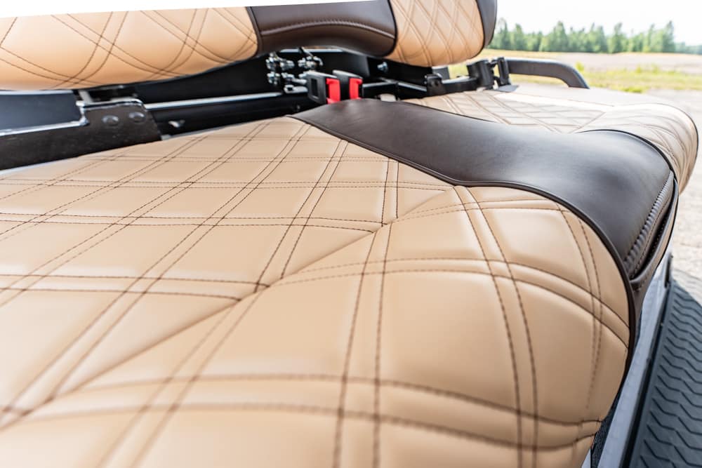 Close-up of tan quilted leather motorcycle seat with a black center panel and visible stitching.