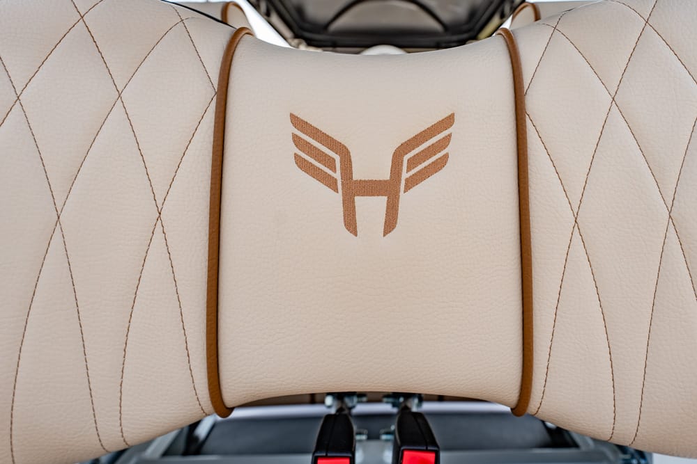 Beige leather car seat headrest with a brown winged 'H' emblem in the center.