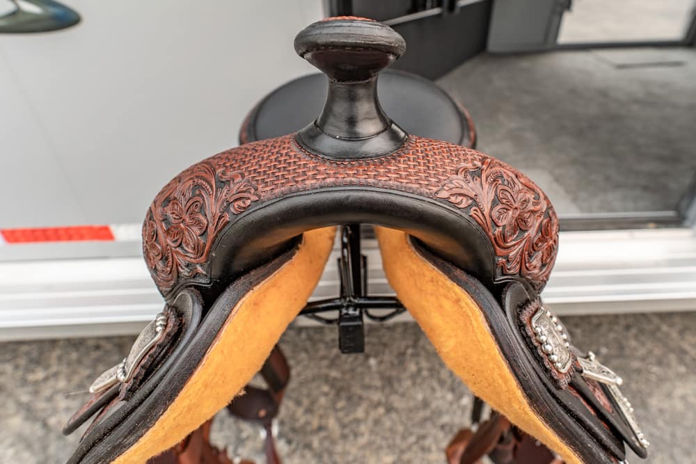 Close-up of a decorative western saddle with floral tooled leather and a horn, viewed from above
