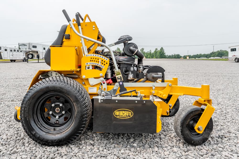 Yellow industrial equipment attachment on gravel, featuring a large rear wheel and a black box labeled 'Qwikchute'