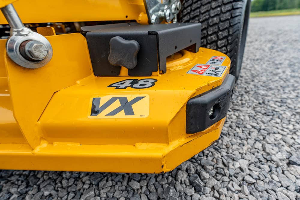 Close-up of a yellow construction plate compactor with a black control knob, labeled VX 48, resting on gravel