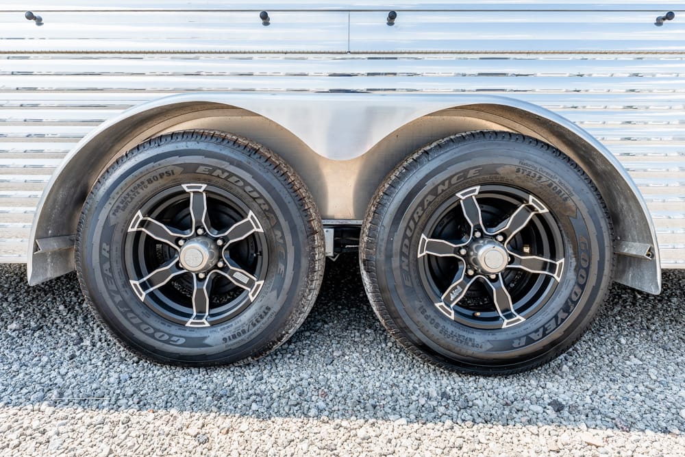 Dual trailer wheels with black rims and Goodyear tires beside a silver trailer body