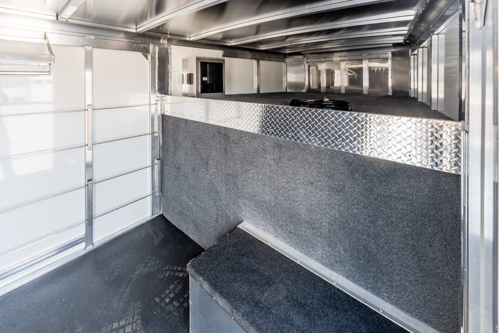 Interior of a metal trailer with diamond-plate trim and a carpeted divider, view toward the back.