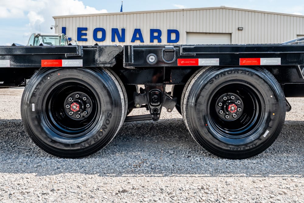 Dual truck tires on a flatbed trailer with a Leonard building in the background