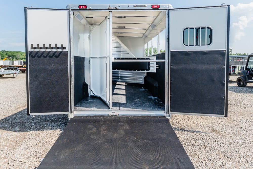 Open horse trailer with ramp down, showing interior stalls and tack storage on the left side area.