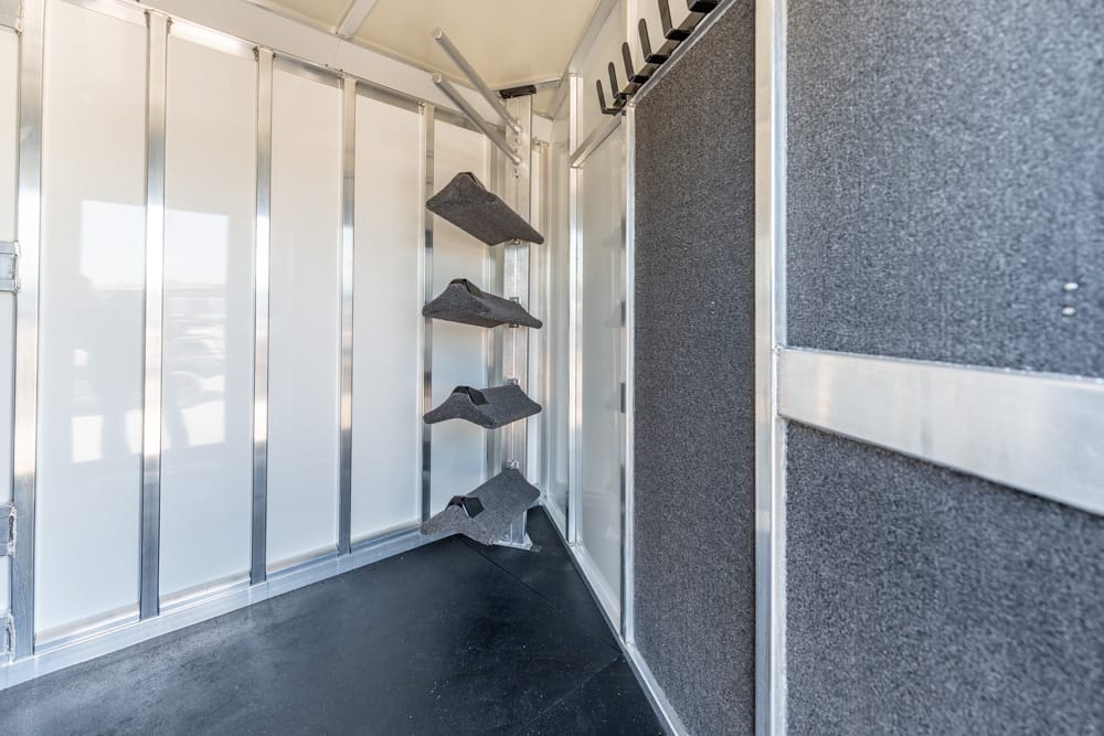 Interior of a metal-walled mobile setup with four angled dark-gray foam pads mounted on a vertical rack against the wall.