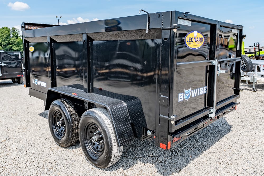Black dual-axle dump trailer on a gravel lot, BowWise logo visible on the side with a Leonard sticker nearby.