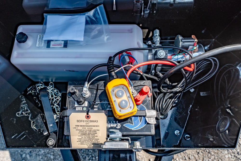 Open battery compartment with a lead-acid battery, red/black cables, and a yellow handheld control switch attached to the terminals?