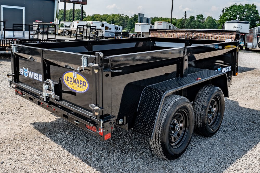 Black dual-axle utility trailer with diamond-plate fenders and Leonard Truck & Trailer decal, parked on a gravel lot.