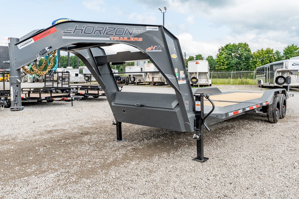 Tilt-bed trailer with a raised gooseneck and hydraulic lift, Horizon Trailers, parked on a gravel lot