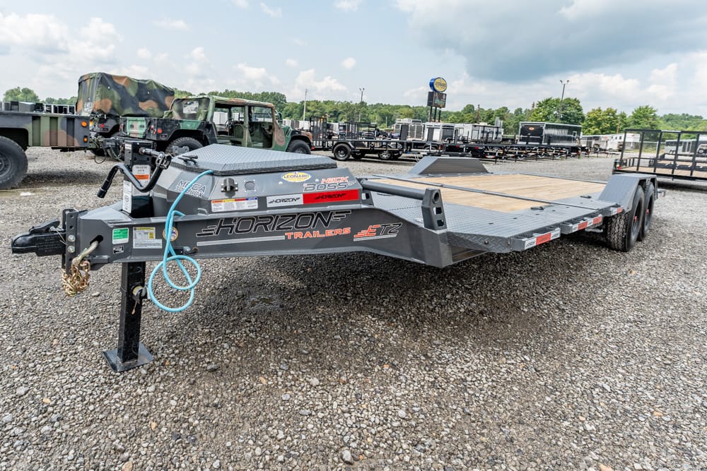 Flatbed gooseneck trailer with Horizon Trailers branding parked on a gravel lot with other trailers in the background.