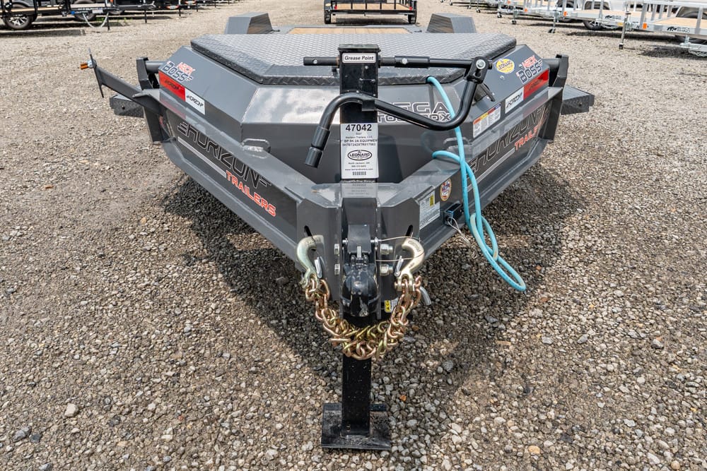 Front view of a gray utility trailer on gravel, showing a diamond-plate top, hitch with safety chains, and a coiled blue hose.