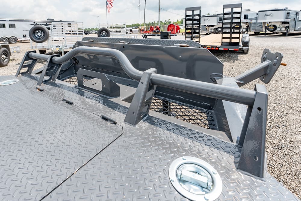 Close-up of a gray diamond-plate flatbed trailer with side rails and towing fittings in a truck trailer yard