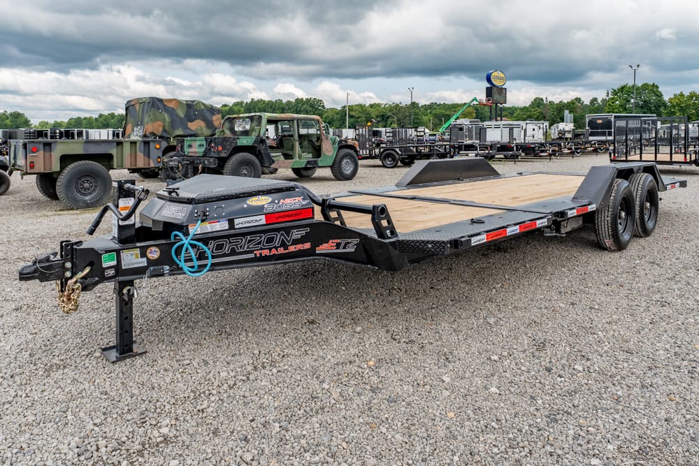 Long flatbed trailer with a wooden deck and dual-axle setup parked in a gravel lot, branded Horizon Trailers