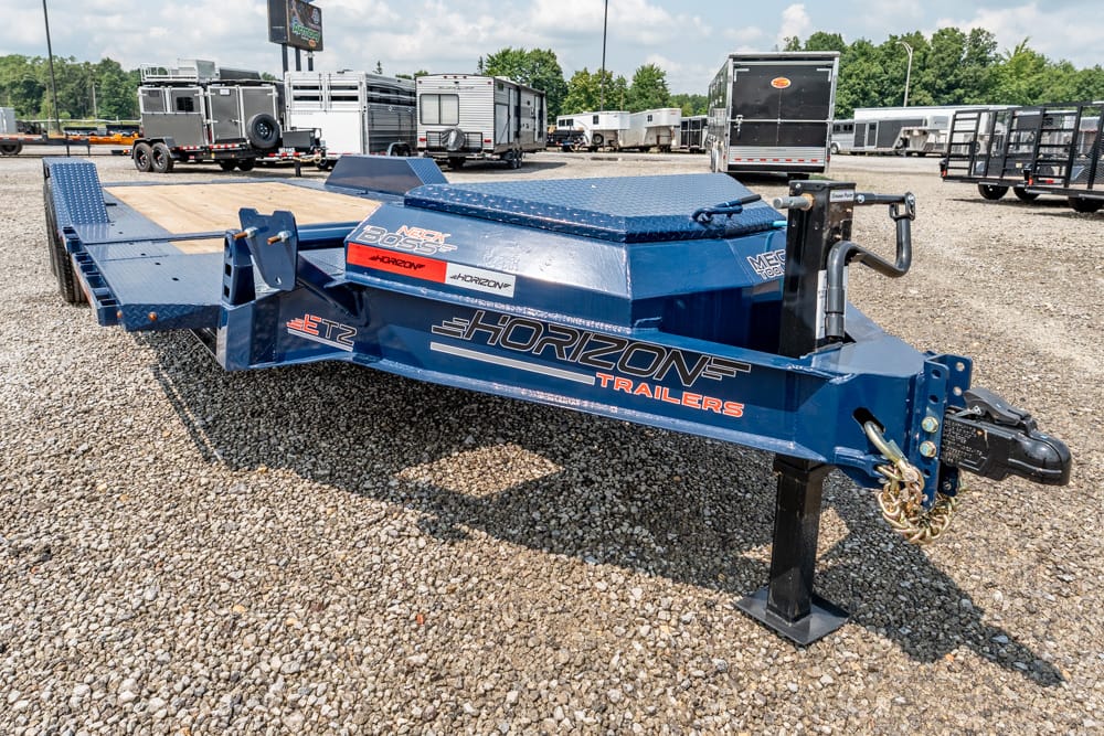 Blue Horizon gooseneck trailer with diamond-plate toolbox and ramps on a gravel lot.