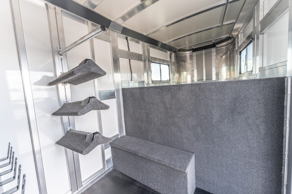 Interior of a metal horse trailer with three foam saddle racks on the left, a padded divider on the right, and a foam block at the front.