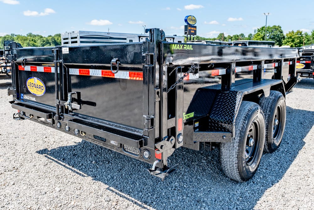 Black dual-axle dump trailer on a gravel lot with MAX RAIL branding and Leonard trailer logo visible at the rear