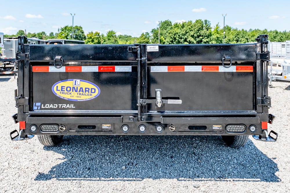 Back of a black dual-axle Load Trail dump trailer with Leonard Truck & Trailer logo on the left, parked on a gravel lot.