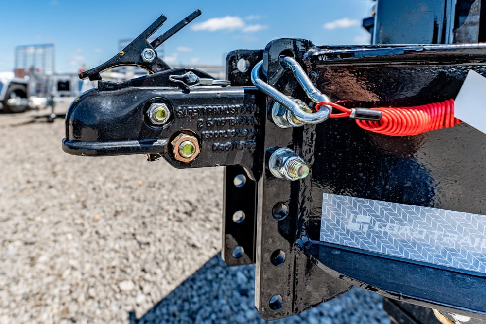 Trailer hitch with safety chains and latch on a black metal frame, ready to connect to a vehicle.