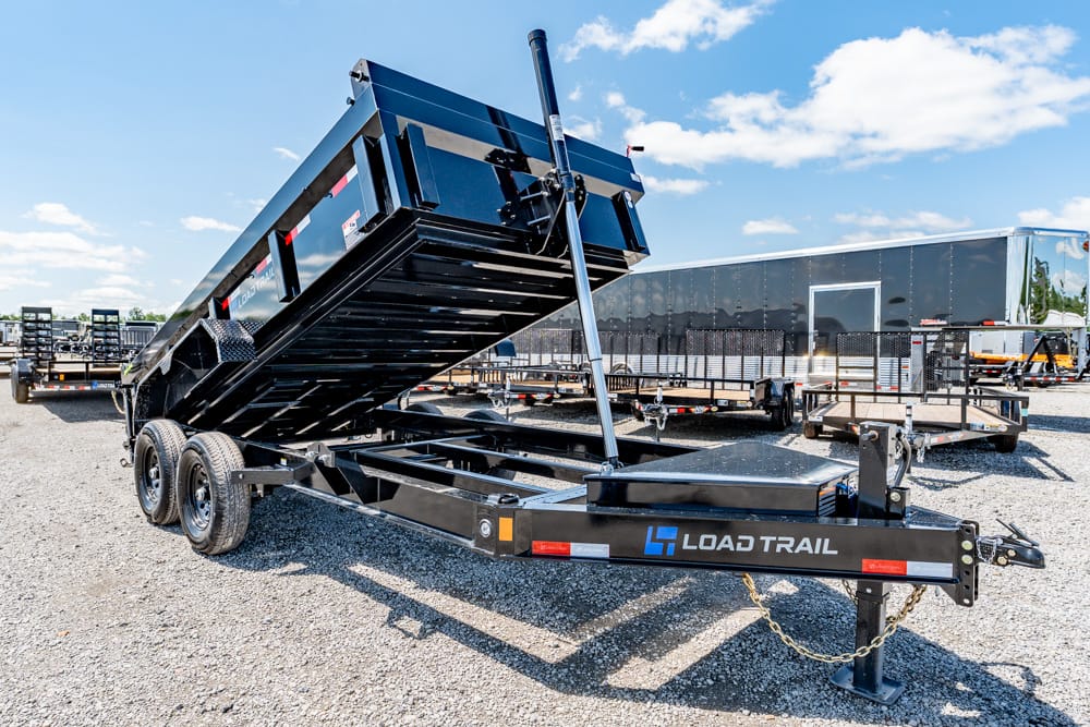 Black Load Trail dump trailer with hydraulic lift raised on a gravel lot, ready for loading.