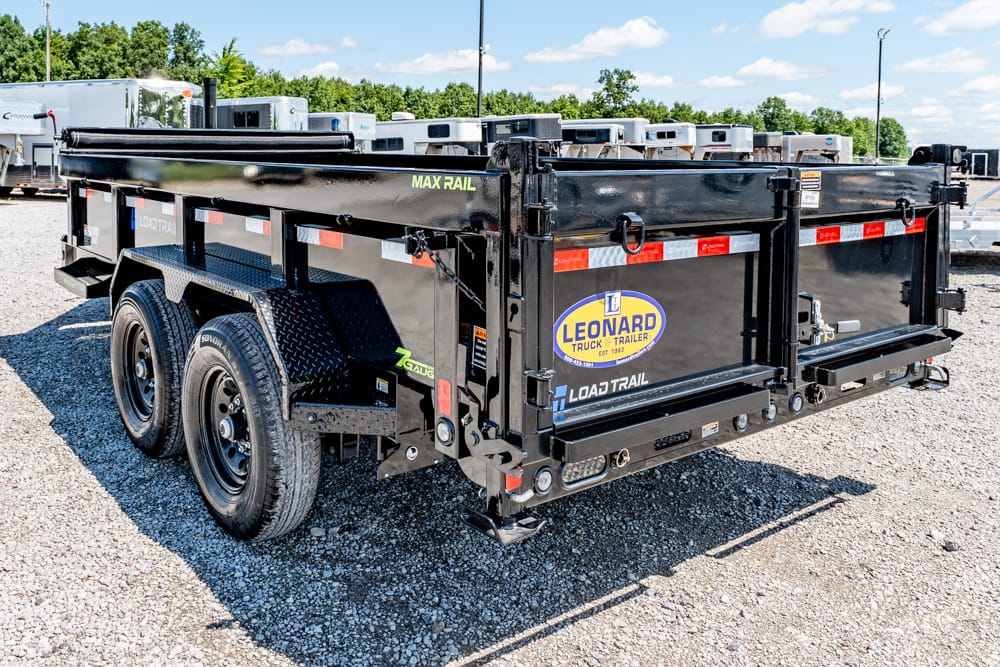 Black tandem-axle Leonard Load Trail trailer parked on gravel; logo and MAX RAIL text visible on the side.
