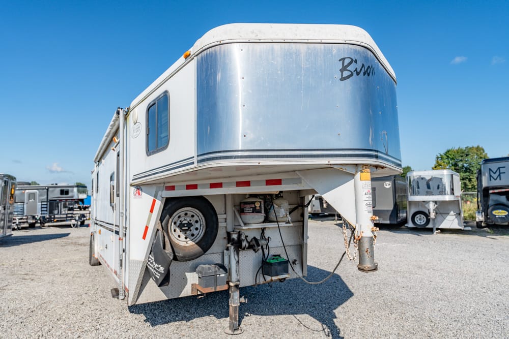 Gooseneck horse trailer parked in a gravel lot with other trailers; front reads 'Bison' on a chrome panel.