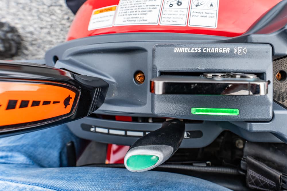 Close-up of a wireless charger on a vehicle dashboard with a green status light on.