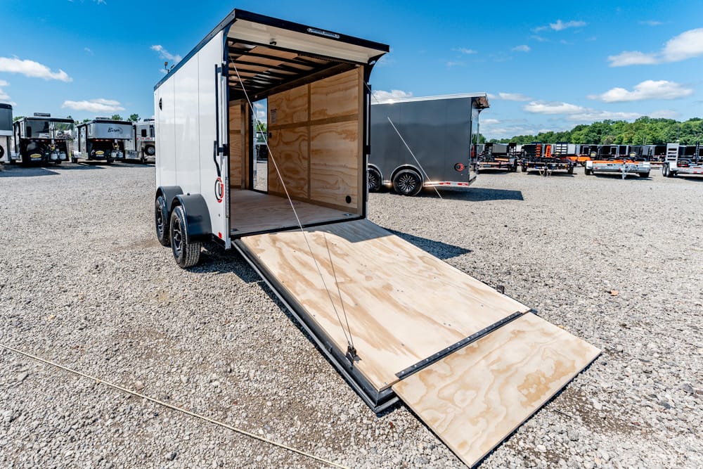 White enclosed cargo trailer with the rear ramp down, empty plywood interior ready for loading.