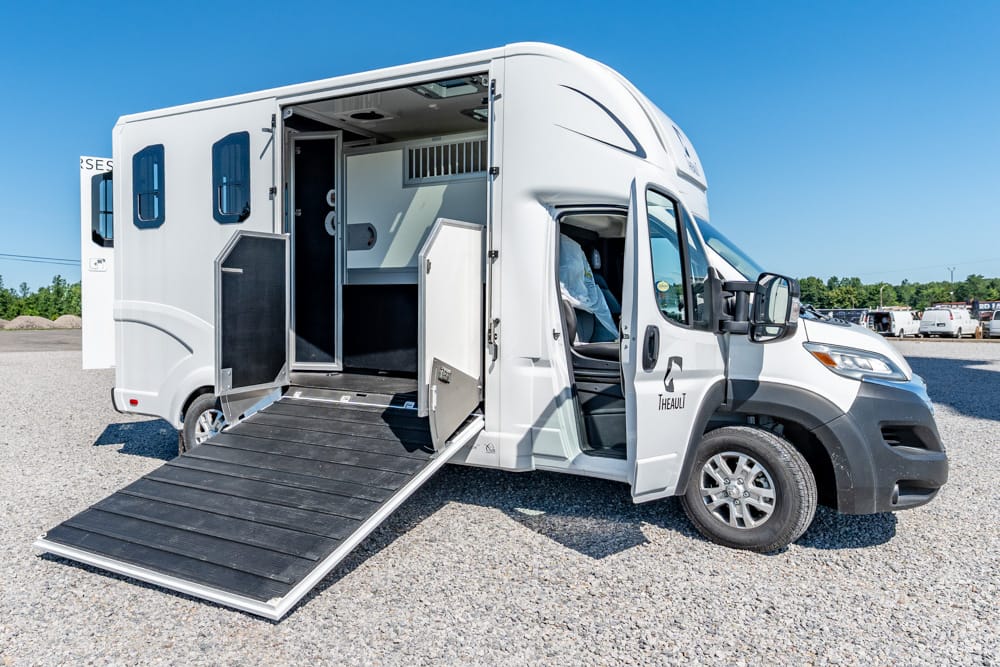 White camper van with a side ramp lowered for accessible entry; interior visible through the open door.