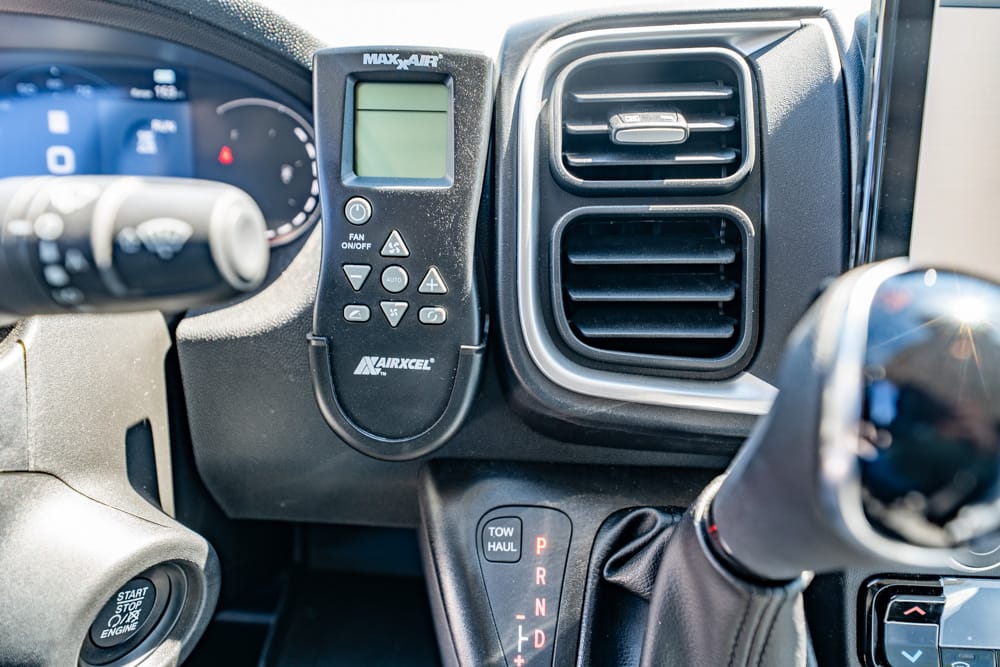 Close-up of a vehicle dashboard showing an HVAC remote, vent, and gear selector (P R N D) with a Start/Stop engine button nearby.