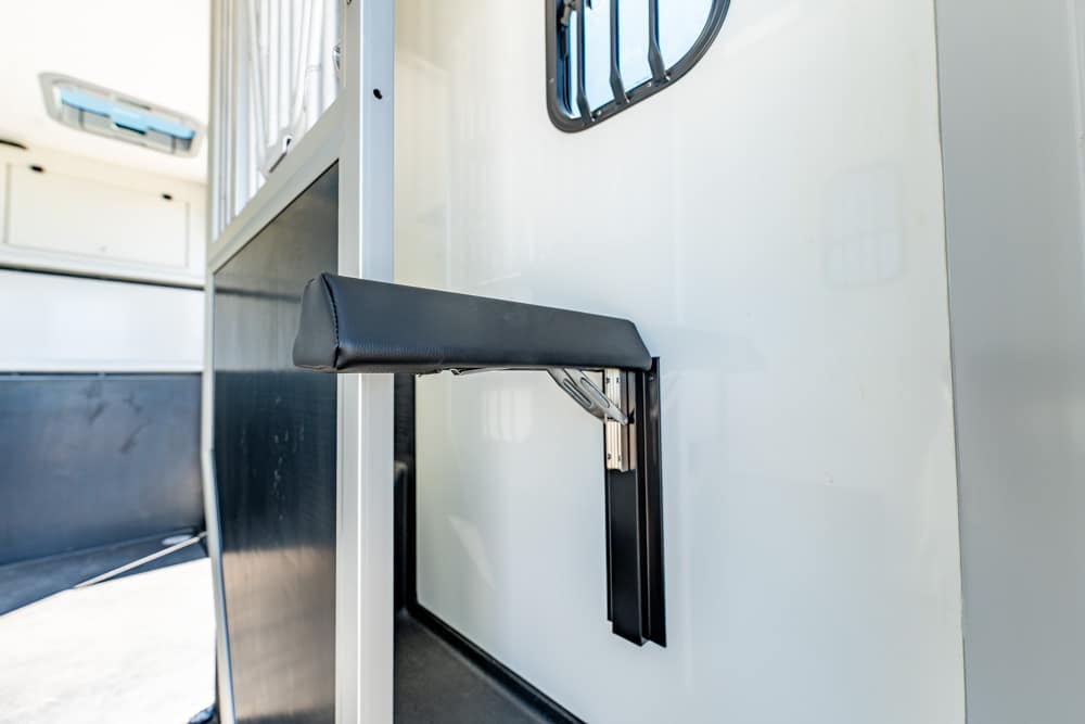 Padded black door handle mounted on a light gray interior wall inside a transport trailer or vehicle.