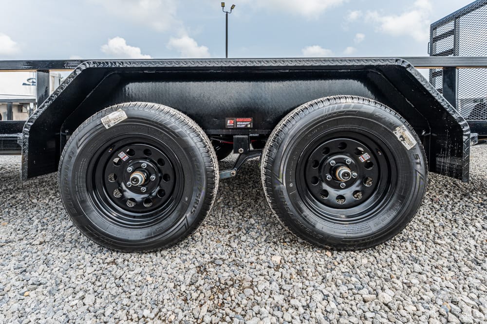 Dual-axle utility trailer wheel and fender on gravel surface