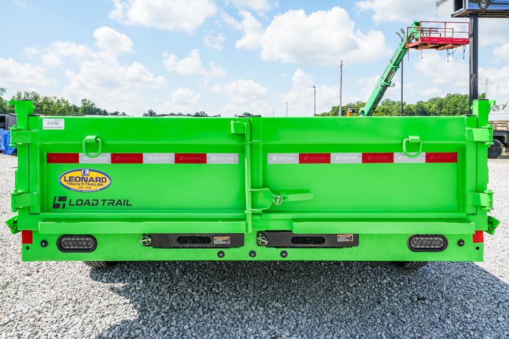 Rear view of a bright green Load Trail dump trailer on a gravel lot, with red/white reflector stripes and logos visible (Leonard and Load Trail).