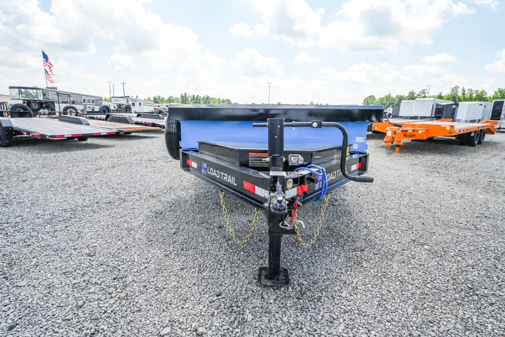 Front view of a black Load Trail trailer hitch on a gravel lot with other trailers in the background