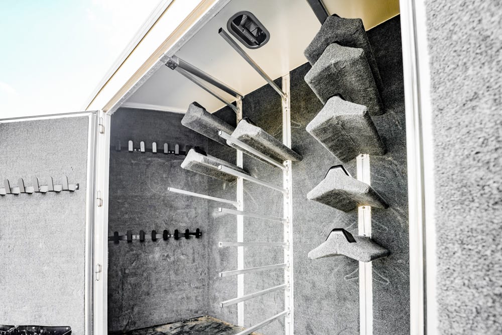Open gun safe interior with foam-lined walls and metal rifle racks (no firearms visible)