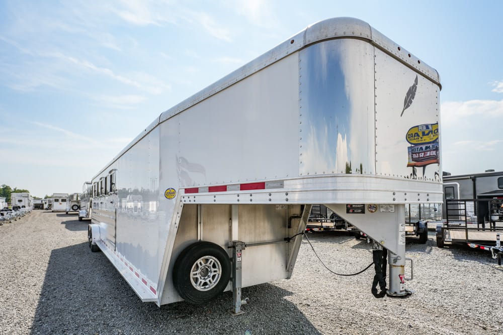White semi-trailer on a gravel lot, reflection of blue sky on polished metal, spare tire mounted on the side.