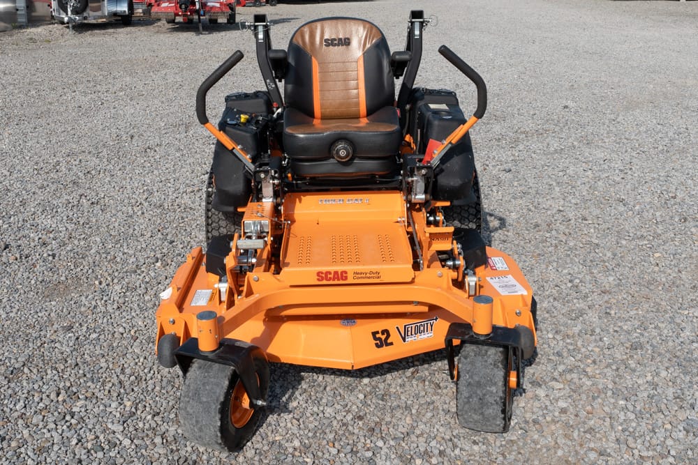 Orange SCAG riding lawn mower with a black-and-tan seat on a gravel lot; 52-inch deck labeled Velocity/Heavy-Duty Commercial.