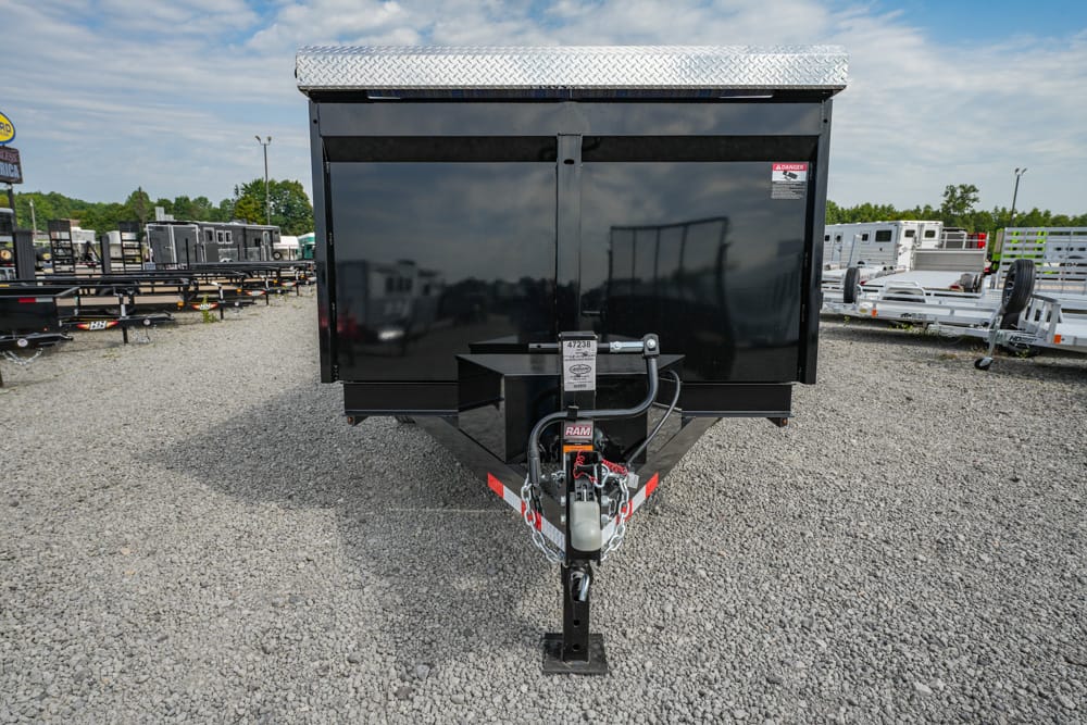 Black utility trailer with a diamond-plate tongue, viewed from the front in a lot of trailers.