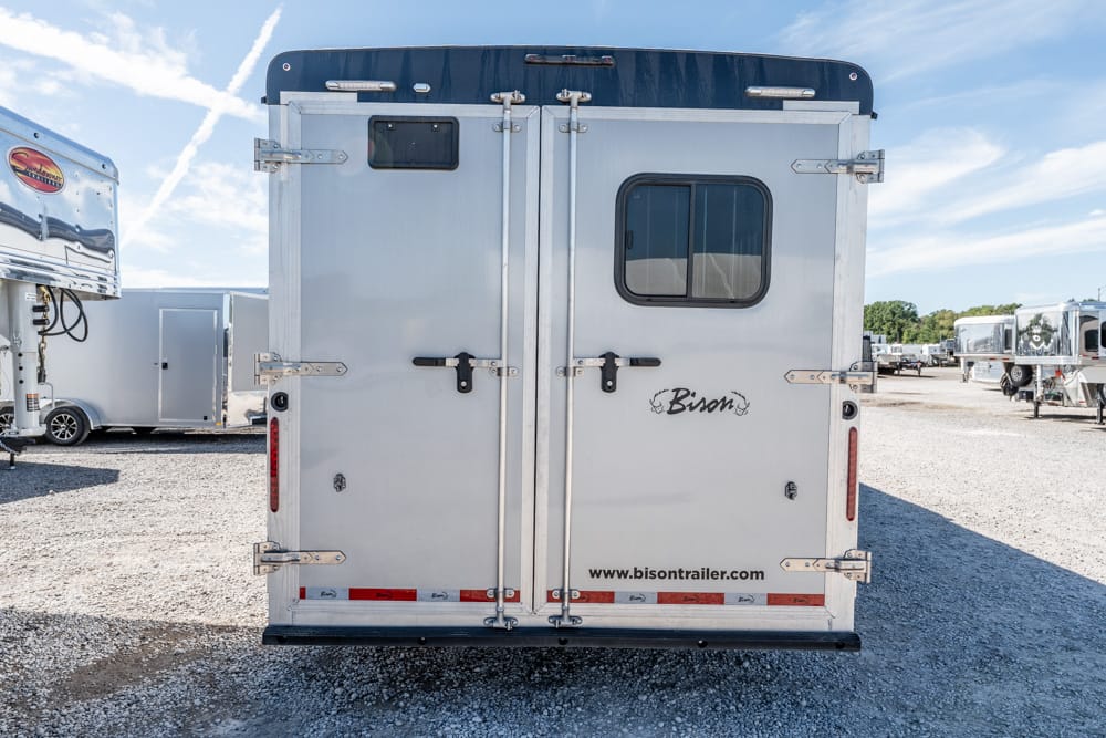 Rear view of a silver Bison horse trailer with a side window, dual doors, and bold latches; website www.bisontrailer.com visible at the bottom.