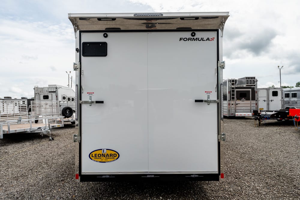Rear of a white enclosed trailer with double doors, Formula logo on the upper right, and a Leonard trailer sticker on the lower left corner.