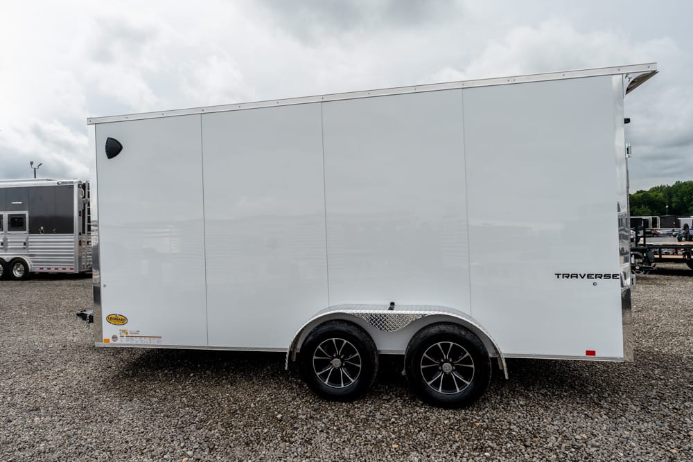 White enclosed cargo trailer with tandem wheels and diamond-plate fender, parked on gravel lot (Traverse logo visible).