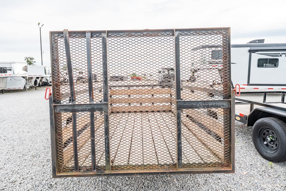 Rusty metal mesh gate closed on a flatbed trailer in a gravel lot, outdoors