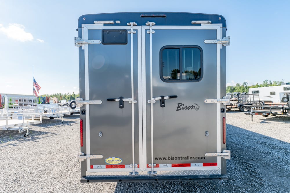 Rear view of a silver Bison horse trailer with double doors, latches, and a small rear window; website www.bisontrailer.com visible on the door.